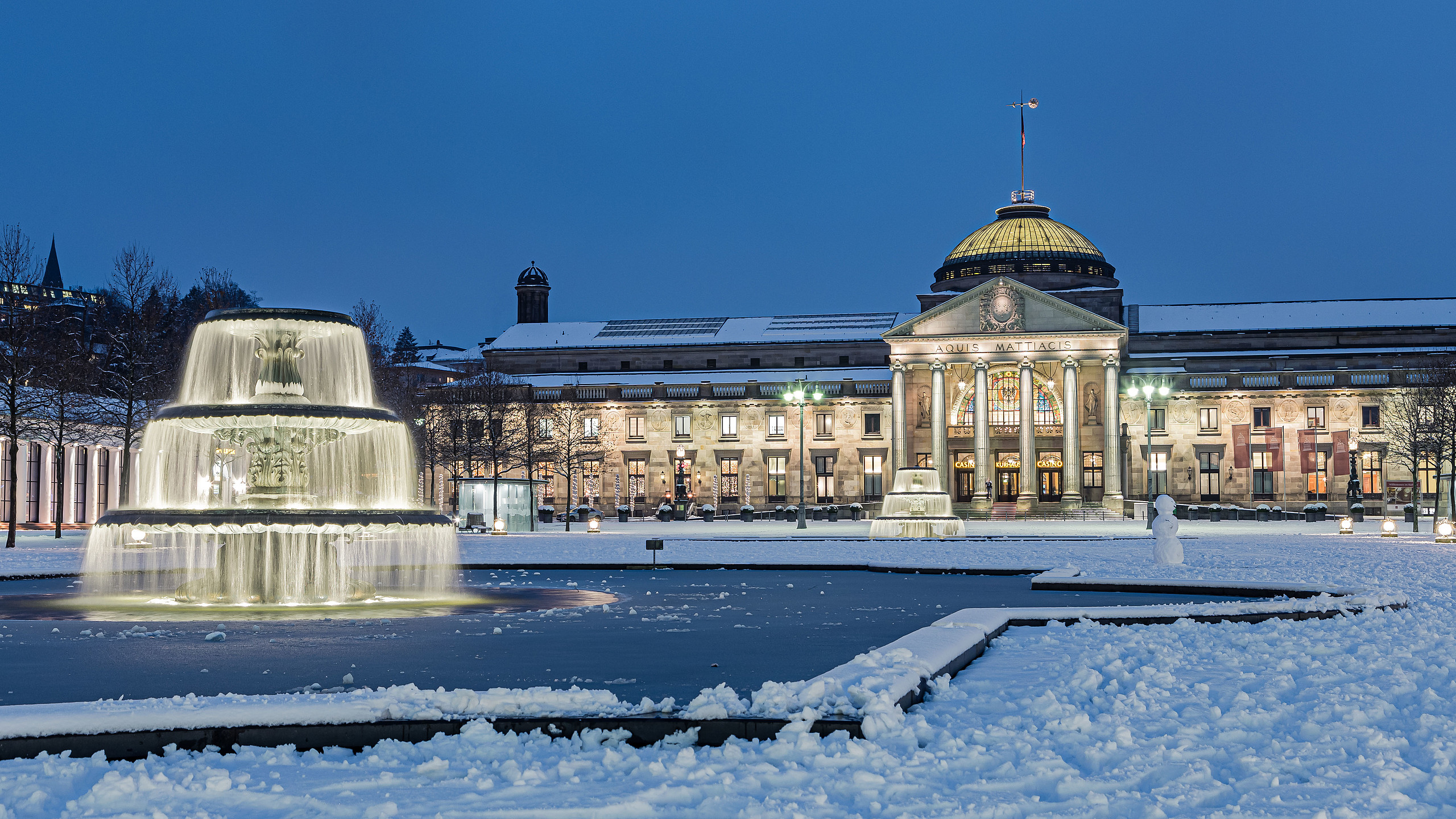 Kurhaus von Wiesbaden im Winter mit beleuchtetem Brunnen davor