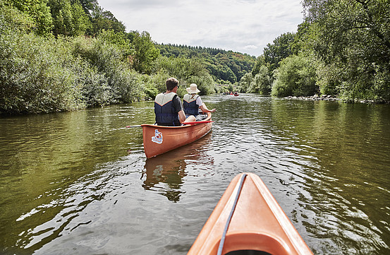 View of canoeists on a river from inside a canoe