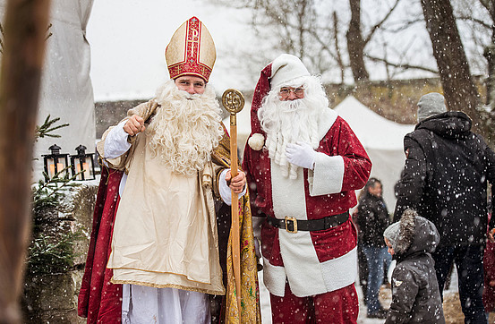 Two white men dressed up as Father Christmas and Nikolaus