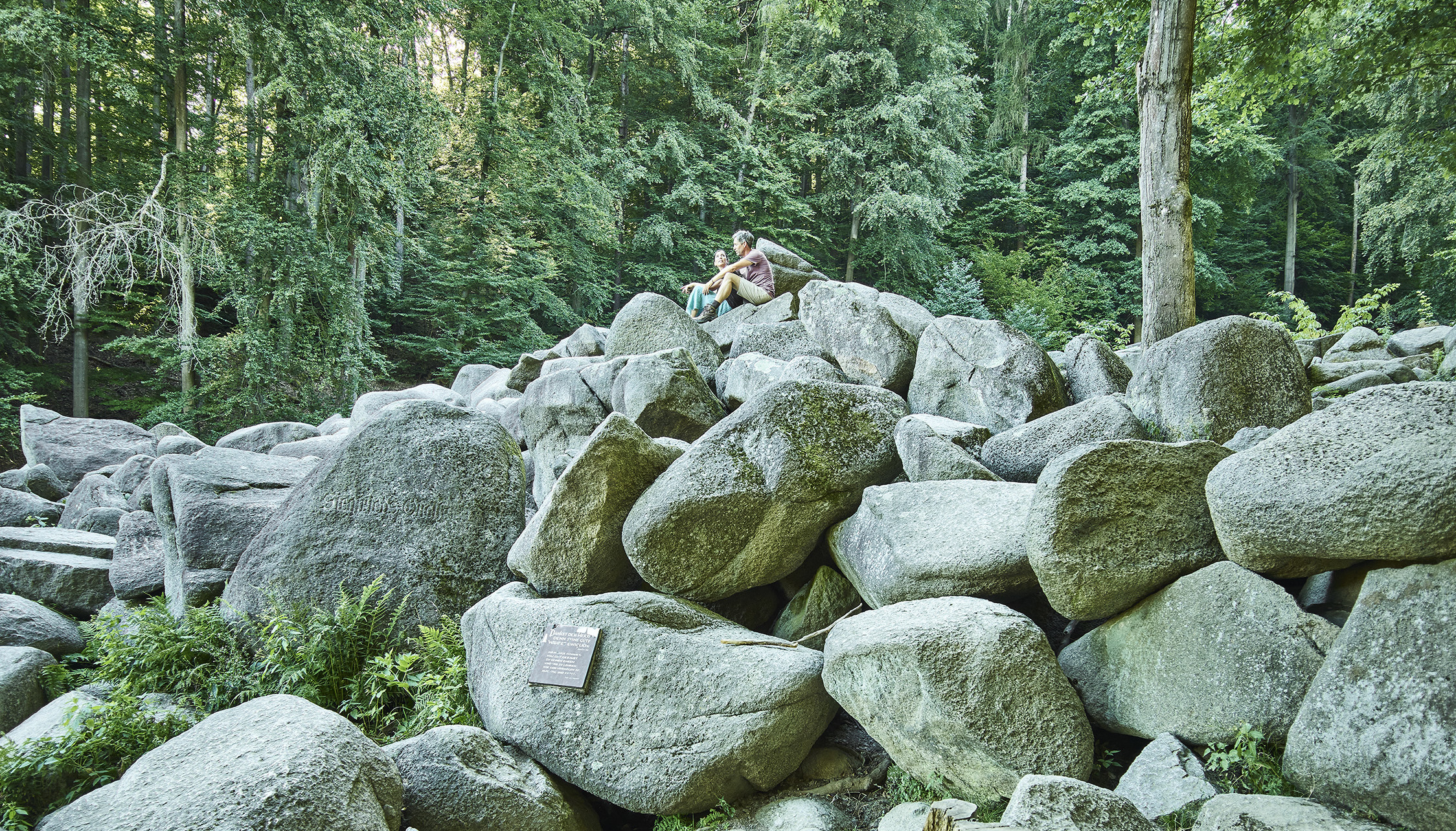 Wanderer sitzen auf den Felsen des Felsenmeers im Odenwald